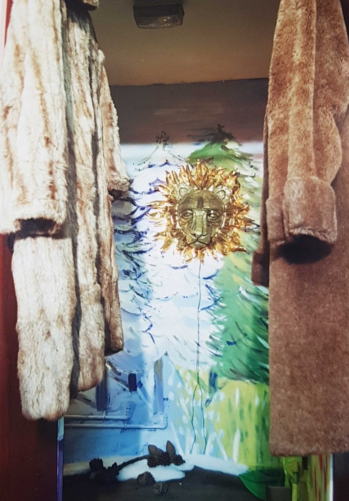 The glorious Aslan, melting the eternal snow, can be seen through the gap in the fur coats.